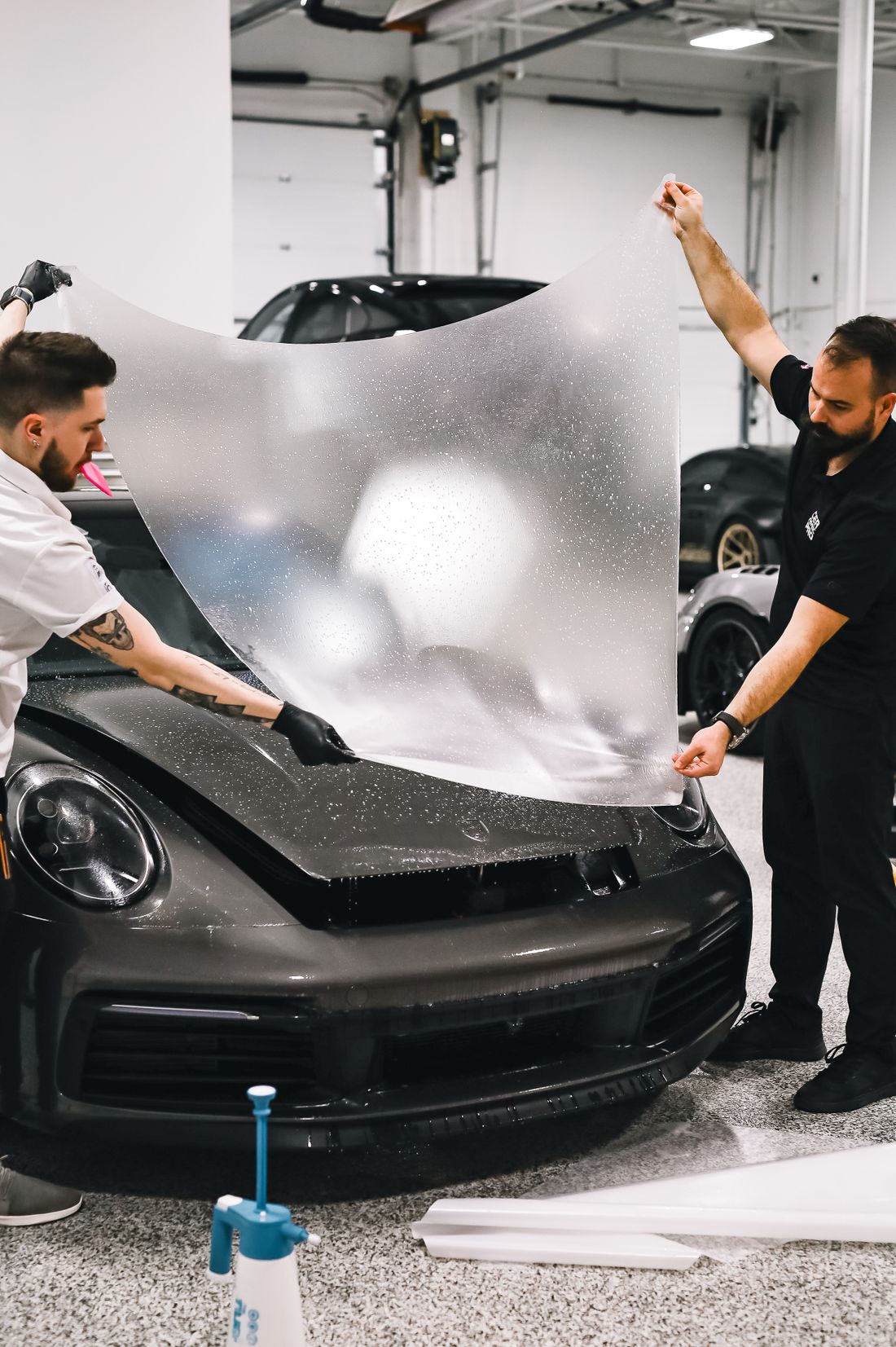 Installers applying paint protection film to a hood